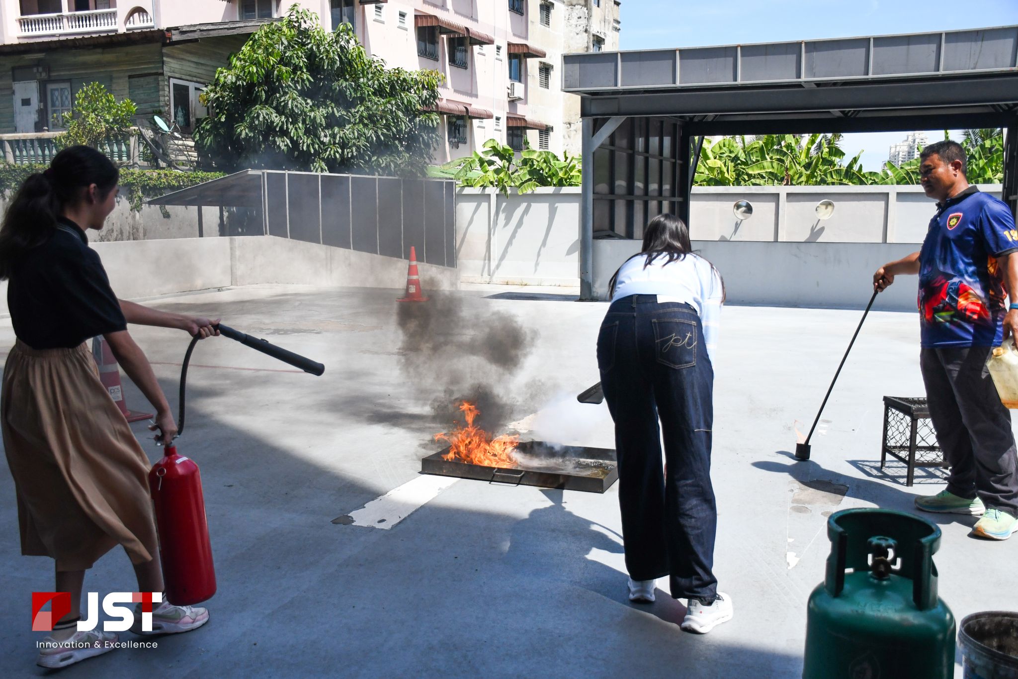 JST Group staff practicing how to operate a fire extinguisher on a controlled fire during evacuation training