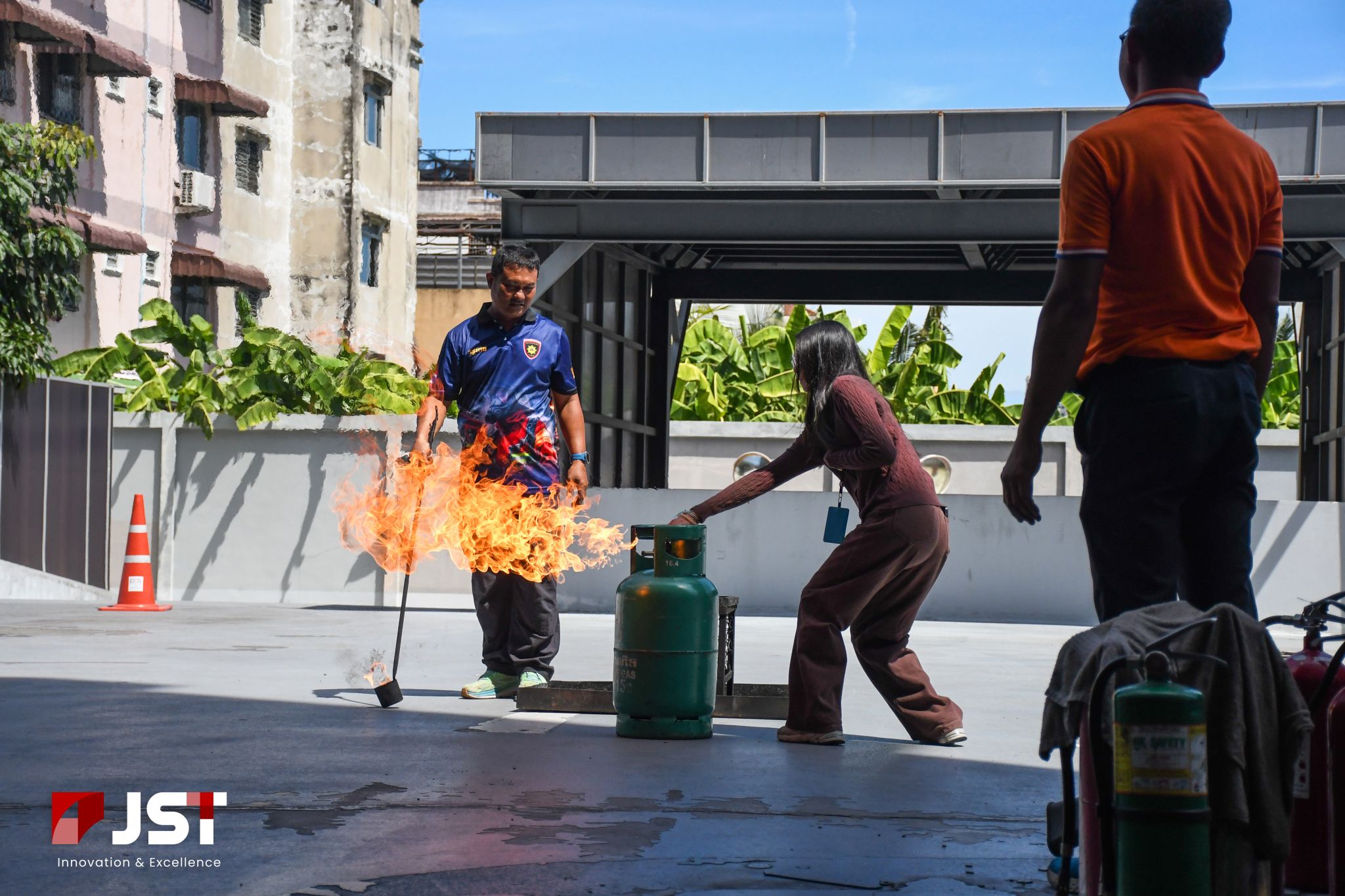 Employee extinguishing a controlled tray fire during JST Group's outdoor fire safety drill at JST Tower
