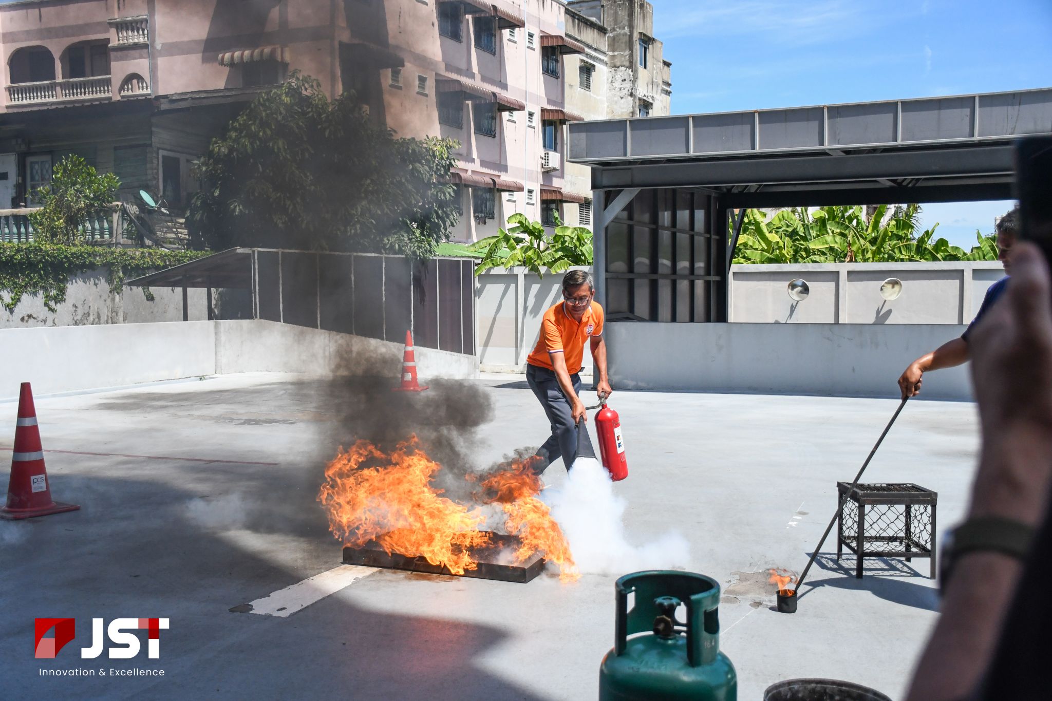 JST Group staff approaching a controlled outdoor fire with a fire extinguisher during evacuation training 2026